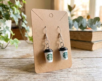 Starbucks-inspired coffee cup dangle earrings featuring miniature white and black cups with the green Starbucks logo.