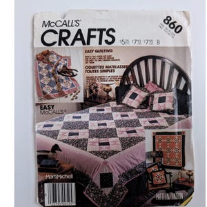 May include: A McCall's Crafts pattern envelope 860 for easy quilting. The front features images of a bedspread and pillows with a pink, navy blue, and white geometric star pattern, along with text including Easy Quilting and Marti Michell.