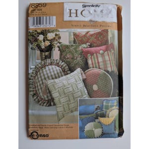 Könnte beinhalten: Eine Simplicity Home Schnittmusterhülle 8859 für Kissen. Das Cover zeigt verschiedene dekorative Kissen in grünen, roten und beigen Stoffen mit Rüschen, Knöpfen und gewebten Texturen. Der Text umfasst Simplicity Home, Simply Beautiful Pillows und Conso.