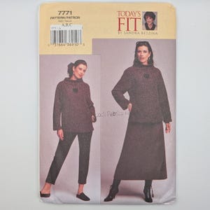 Puede incluir: Un sobre de patrón de costura Today's Fit de Sandra Betzina, número 7771, con ilustraciones de una blusa de manga larga con cuello alto combinada con pantalones ajustados o una falda larga. El paquete incluye un código de barras y texto.