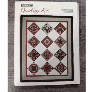 May include: A Lands' End Quilling Kit instructional booklet featuring a quilt design with twelve diamond-shaped blocks. Each block displays unique geometric, floral, and bird patterns in shades of red, brown, and white, framed by a dark border.