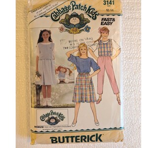 May include: A Butterick sewing pattern envelope for Cabbage Patch Kids clothing, size 12-14. The front features illustrations of outfits including a light blue dress, a plaid skirt with a blue top, and a plaid top with pink pants, plus a doll.