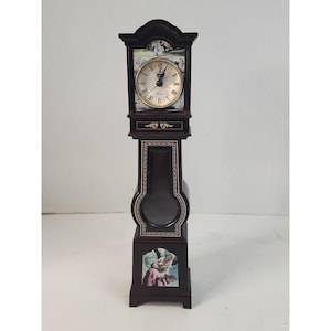 May include: A tall, dark brown wooden grandfather clock featuring a round clock face with Roman numerals and the word Quartz. The clock body is decorated with gold-colored trim and two rectangular panels depicting colorful painted figures.