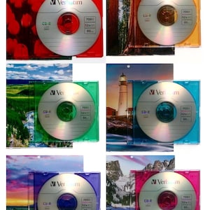May include: A collection of six Verbatim CD-R discs, each housed in a transparent colored plastic case featuring a unique landscape or floral background image. The discs are silver with printed text including 700MB, 52x, and 80 minutes.