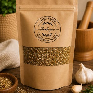 Peut inclure: Un sachet debout en papier kraft brun avec une fenêtre transparente contenant un mélange d'épices grossier et multicolore. Une étiquette circulaire sur le devant porte le texte Casa Elena, thank you, et Homemade with Love en noir.