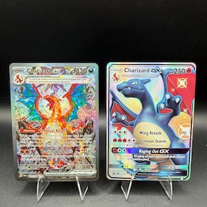 May include: Two collectible trading cards featuring Charizard. The left card is a holographic Charizard ex with 330 HP, while the right card is a shiny Charizard GX with 250 HP. Both cards display detailed character illustrations, text, and game stats.