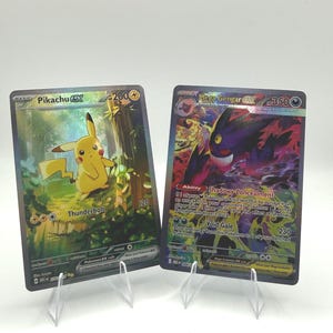 May include: Two rectangular trading cards featuring Pikachu EX with 200 HP and Mega Gengar EX with 350 HP. The Pikachu card shows a yellow character in a forest, while the Mega Gengar card displays a purple creature with glowing eyes.