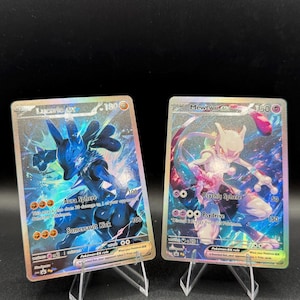 May include: Two holographic Pokémon trading cards featuring Lucario ex and Mewtwo ex. The Lucario card displays a blue character with Aura Sphere and Somersault Kick attacks. The Mewtwo card shows a purple character with Psychic Sphere and Psydrive attacks.
