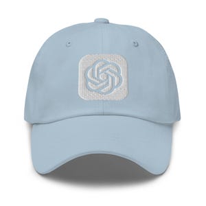Könnte beinhalten: Eine hellblaue Baseballkappe mit einem weißen, aufgestickten quadratischen Aufnäher auf der Vorderseite. Der Aufnäher zeigt ein weißes, geometrisches, knotenartiges Logo in der Mitte. Die Kappe hat einen gebogenen Schirm und gestickte Ösen.