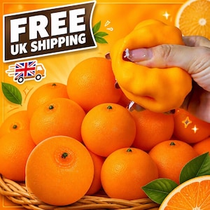 Könnte beinhalten: Eine Ansammlung leuchtend orangefarbener Zitrusfrüchte in einem geflochtenen Korb, wobei eine Orange von einer Hand zusammengedrückt wird. Die Orangen haben eine strukturierte, genoppte Schale und eine runde Form. Grüne Blätter liegen zwischen den Früchten.