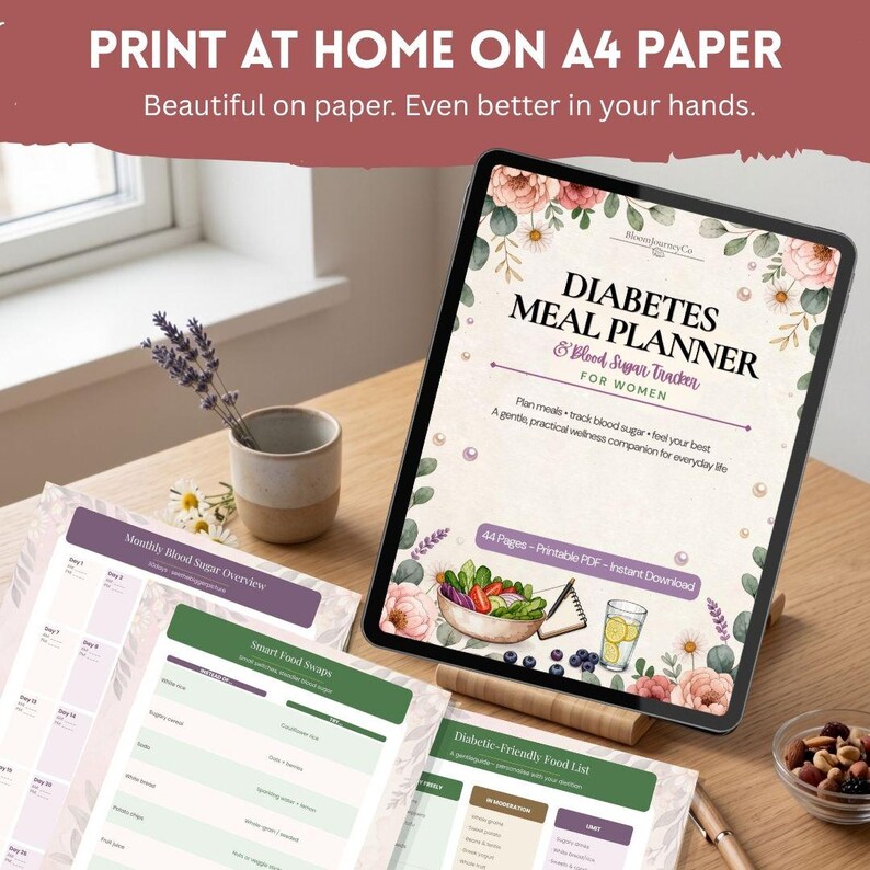 Puede incluir: Una tableta digital muestra un PDF de planificador de comidas y rastreador de az&uacute;car en sangre con ilustraciones florales. La pantalla muestra el t&iacute;tulo, 44 p&aacute;ginas y gr&aacute;ficos de alimentos. P&aacute;ginas impresas con tablas est&aacute;n dispuestas cerca.