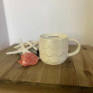 This is a Starbucks Twilight Shimmer Pearl White Scales mermaid siren scale pattern ceramic. This is a Starbucks anniversary collector mug.