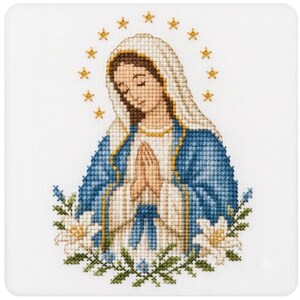 May include: A cross-stitch embroidery depicting a figure with brown hair wearing a white head covering and a blue robe, hands clasped in prayer. A halo of twelve yellow stars surrounds the head, and white lilies with green leaves are at the base.