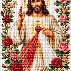 Puede incluir: Un bordado en punto de cruz que representa a Jesucristo con halo, vistiendo una túnica blanca con rayos rojos y blancos que emanan del pecho. La figura está enmarcada por un borde de rosas rojas y rosas con hojas verdes sobre tela.