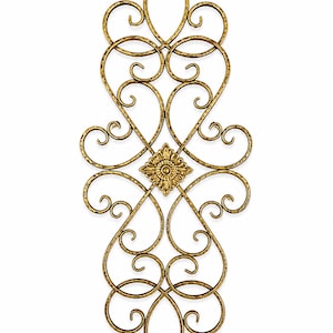 May include: A gold-colored metal wall decor piece featuring an intricate arrangement of symmetrical scrolls and curves. The design includes a central square floral medallion with detailed petals, surrounded by a continuous frame of hammered metal wire.