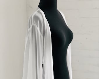 May include: A white sheer long-sleeved cardigan with a loose fit and a flowing silhouette.