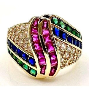 May include: A gold ring featuring a central vertical band of baguette-cut pink stones flanked by rows of channel-set blue and green stones. The design includes sections of pavé-set clear stones arranged in a curved, multi-layered pattern.