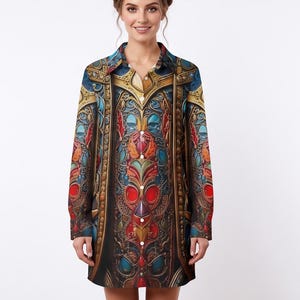 Puede incluir: Un vestido camisero de manga larga con botones que presenta un patrón vibrante e intrincado en tonos rojo, azul, dorado y negro. El diseño incluye motivos ornamentales y simétricos que recuerdan a la orfebrería o filigrana.