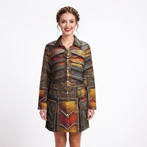 Könnte beinhalten: Ein langärmeliges Hemdkleid mit durchgehender Knopfleiste und einem detaillierten Grafikdruck von metallischer mittelalterlicher Rüstung in Gold-, Rost- und Dunkelgrautönen. Das Kleidungsstück verfügt über einen klassischen Kragen und einen geraden Saum.