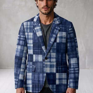 May include: A blue and white plaid blazer featuring a patchwork design with various checkered patterns, a notched lapel, a single front button closure, and two flap pockets, worn over a plain dark gray crew neck shirt.