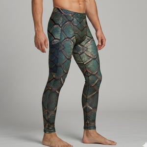 Peut inclure: Legging vert et bronze avec un motif d'écailles. Le legging présente un motif détaillé qui ressemble à des écailles de reptile. La palette de couleurs comprend des nuances de vert, de bronze et de noir, créant un aspect texturé. Le legging est moulant.