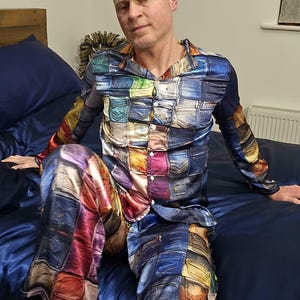 May include: A vibrant pajama set with a denim patchwork pattern. The long-sleeved top and trousers are made of a silky fabric. The pyjamas are in shades of blue, red, yellow, and green.