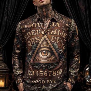 May include: A brown long-sleeved shirt with a Ouija board print. The design includes an eye within a triangle, numbers, letters, and the words "YES," "NO," and "GOOD BYE." This shirt is part of a gothic fashion collection.