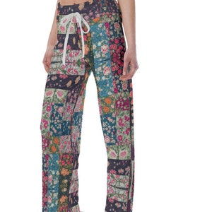 May include: Wide-leg pants with a patchwork design featuring floral patterns in shades of pink, blue, green, and orange. The pants have a drawstring waist and a relaxed fit.