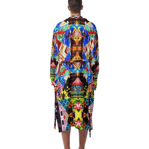 Op de afbeelding: Een badjas met patronen met een levendige mix van blauwe, rode, gele en zwarte geometrische vormen. De badjas heeft lange mouwen en een ceintuur. Het ontwerp is symmetrisch en creëert een gedurfde en opvallende look.