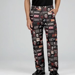 May include: Black pants with a repeating pattern of skulls, text, and keyboard keys. The text includes words like "Dissent" and "Detest" in red and white. The pants have a classic five-pocket design.