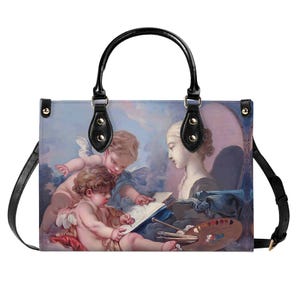 Può includere: Una borsa tote in pelle nera con un dipinto colorato di due cherubini e una donna. Il dipinto raffigura i cherubini che disegnano su un pezzo di carta mentre la donna osserva. La borsa ha un manico superiore e una tracolla.