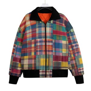 Peut inclure: Veste patchwork multicolore avec col, poignets et ourlet noirs. La veste est dotée d'une fermeture éclair sur toute la longueur et d'une doublure matelassée orange. Le patchwork comprend divers motifs à carreaux dans des tons de rouge, bleu, jaune et vert.