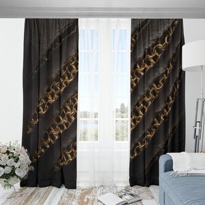 May include: Black window curtains with diagonal gold chainmail pattern. The curtains are made of a textured fabric and hang in front of a white window. A vase of white flowers sits on the floor.