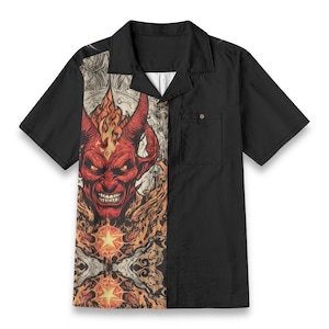 Könnte beinhalten: Ein schwarzes, kurzärmeliges Hemd mit Knöpfen und einem roten Teufelskopf mit Flammengrafik auf der linken Seite. Die rechte Seite des Hemdes ist einfarbig schwarz.