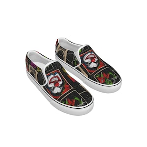 May include: Pair of black slip-on shoes with a colorful, scary clown face design. The shoes have white soles and a white trim around the opening. The clown has red lips and nose, with green and red accents.