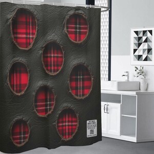 May include: Black shower curtain featuring oval apertures displaying a red and black tartan design. The curtain has a textured finish and is displayed in a bathroom. A white label with text is visible.