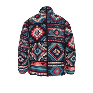 Op de afbeelding: Een gewatteerde jas met een geometrisch patroon in tinten rood, blauwgroen en crème. De jas heeft een hoge kraag en een ritssluiting over de hele lengte. Het ontwerp bestaat uit verschillende vormen en patronen, waardoor een patchwork-effect ontstaat. De jas is van gemiddeld gewicht en geschikt voor koeler weer.