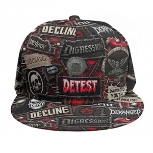 Pode incluir: Boné de beisebol preto e vermelho com aba reta e design de patchwork. O boné apresenta patches com textos como "DETEST", "DECLINE" e "DIGRESSION", juntamente com gráficos de caveira e águia. A aba também é preta e vermelha.