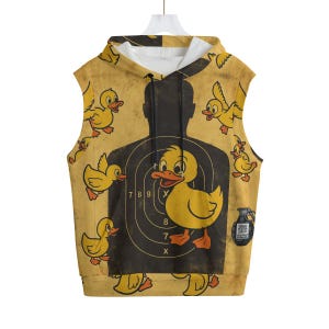 Op de afbeelding: Gele mouwloze hoodie met een cartoon eend doel ontwerp. Het ontwerp toont een eend in het midden van een doel, omringd door andere eenden en een silhouet van een persoon. De achtergrond is een verweerd geel.