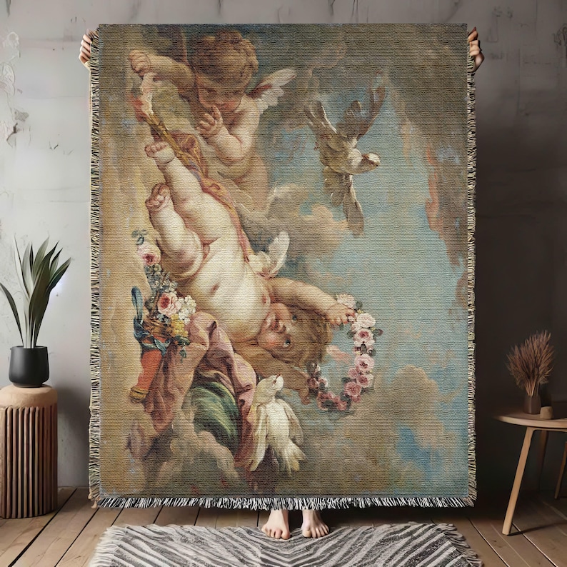 May include: A tapestry featuring a painting of three cherubs in a sky with clouds. The cherubs are depicted with wings and are holding a wreath of flowers. The tapestry is woven with a detailed design and has a fringed border.