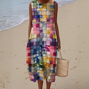 Puede incluir: Vestido sin mangas, hasta la rodilla, con un vibrante diseño de patchwork geométrico en tonos azules, rosas, amarillos y morados. El vestido tiene dos bolsillos y se combina con un bolso tote tejido. La imagen está tomada en una playa de arena.