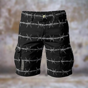 May include: Black cargo shorts featuring a white barbed wire design. The shorts have two side pockets and a button fastening. The material looks like a robust cotton blend. These shorts are designed for casual wear.