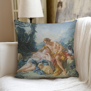 May include: Square throw pillow featuring a classical painting of two figures in a pastoral setting. The artwork depicts a man and woman, with a dog and sheep, in shades of blue, yellow, and green. The pillow is placed on a white couch.