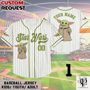 Puede incluir: Una camiseta de b&eacute;isbol blanca con rayas diplom&aacute;ticas de color verde oliva, con el texto Star Wars y el n&uacute;mero 00 en la parte delantera, y un gr&aacute;fico de una criatura verde con t&uacute;nica beige delante y detr&aacute;s. La espalda incluye el texto YOUR NAME.