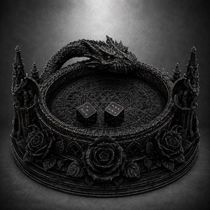 May include: A circular black dice tray featuring a sculpted dragon head wrapping around the rim, two gargoyle figures on pillars, and three roses at the base. The interior floor displays an engraved pentagram and symbols, with two black dice.