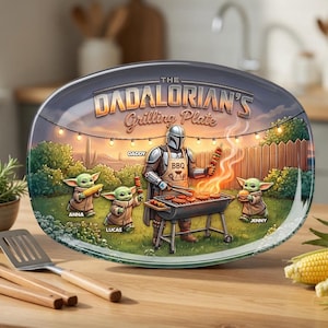 Peut inclure: Un plateau de service ovale avec une illustration graphique d'un personnage en armure argentée faisant griller des aliments. Le texte indique THE DADALORIAN'S Grilling Plate, DADDY, ANNA, LUCAS et JENNY. Trois petites créatures vertes en robe.