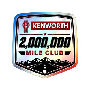 May include: A shield-shaped sticker with a holographic finish featuring the Kenworth logo, the text 2,000,000 MILE CLUB, a red star, and a black graphic of a road leading toward a mountain range against a metallic silver background.