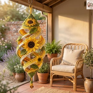 May include: A hanging crochet spiral wind spinner featuring yellow sunflower motifs with dark brown centers and green leaves. The yarn structure is layered in a conical shape, suspended from a metal hook, showcasing intricate stitching and textures.