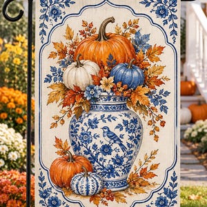 May include: A rectangular garden flag featuring a blue and white porcelain-style vase filled with orange, white, and blue pumpkins and autumn leaves. A small blue bird is illustrated on the vase, surrounded by floral patterns and a decorative border.