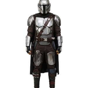 May include: A full-body suit of silver metallic armour featuring a rounded helmet with a T-shaped visor, shoulder pauldrons, gauntlets, and leg plating. The armour is worn over a dark brown textured fabric jumpsuit with a utility belt and bandolier.
